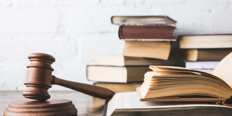 opened juridical books with gavel on wooden table, law concept